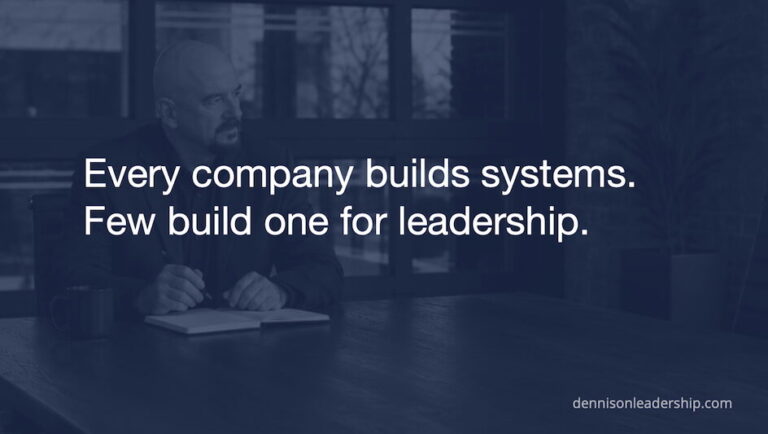 Mike Dennison working at a laptop representing the need for a structured leadership development system as organizations grow.
